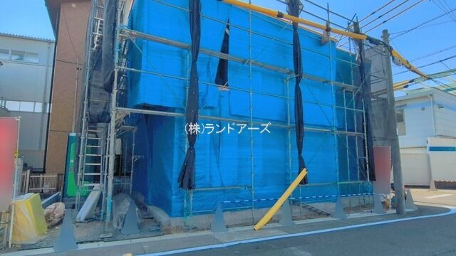 Building under construction wrapped in blue tarp with scaffolding on a residential street outside. (informative)