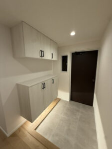 Entryway with two-tone gray wall cabinets (upper and lower), a light wood base, and a dark front door.